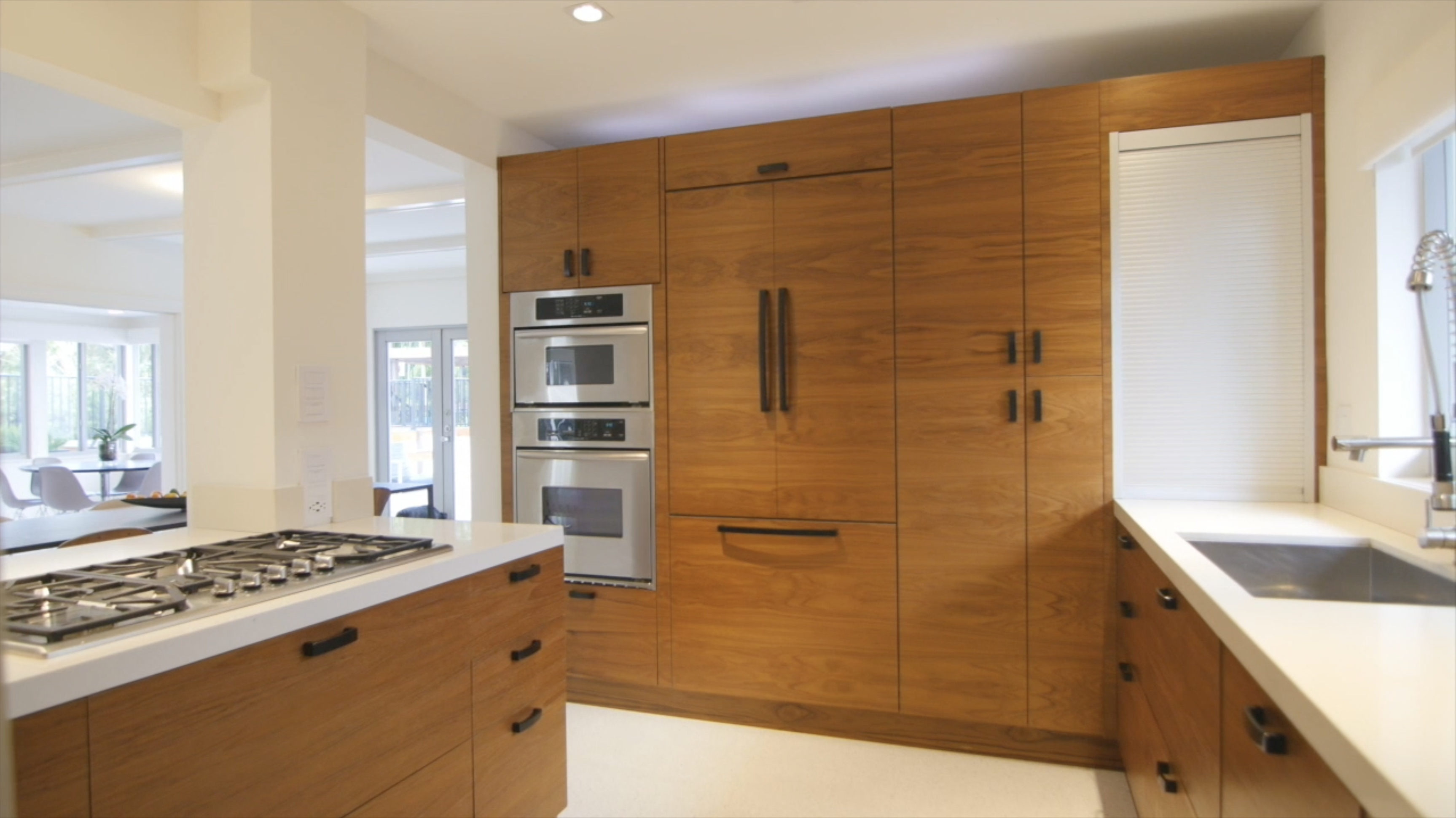 Euro Finishes luxury kitchen renovation showcase - European minimalist design with clean lines, natural wood cabinetry, integrated appliances, and sophisticated restraint exemplifying high-end Miami residential construction craftsmanship